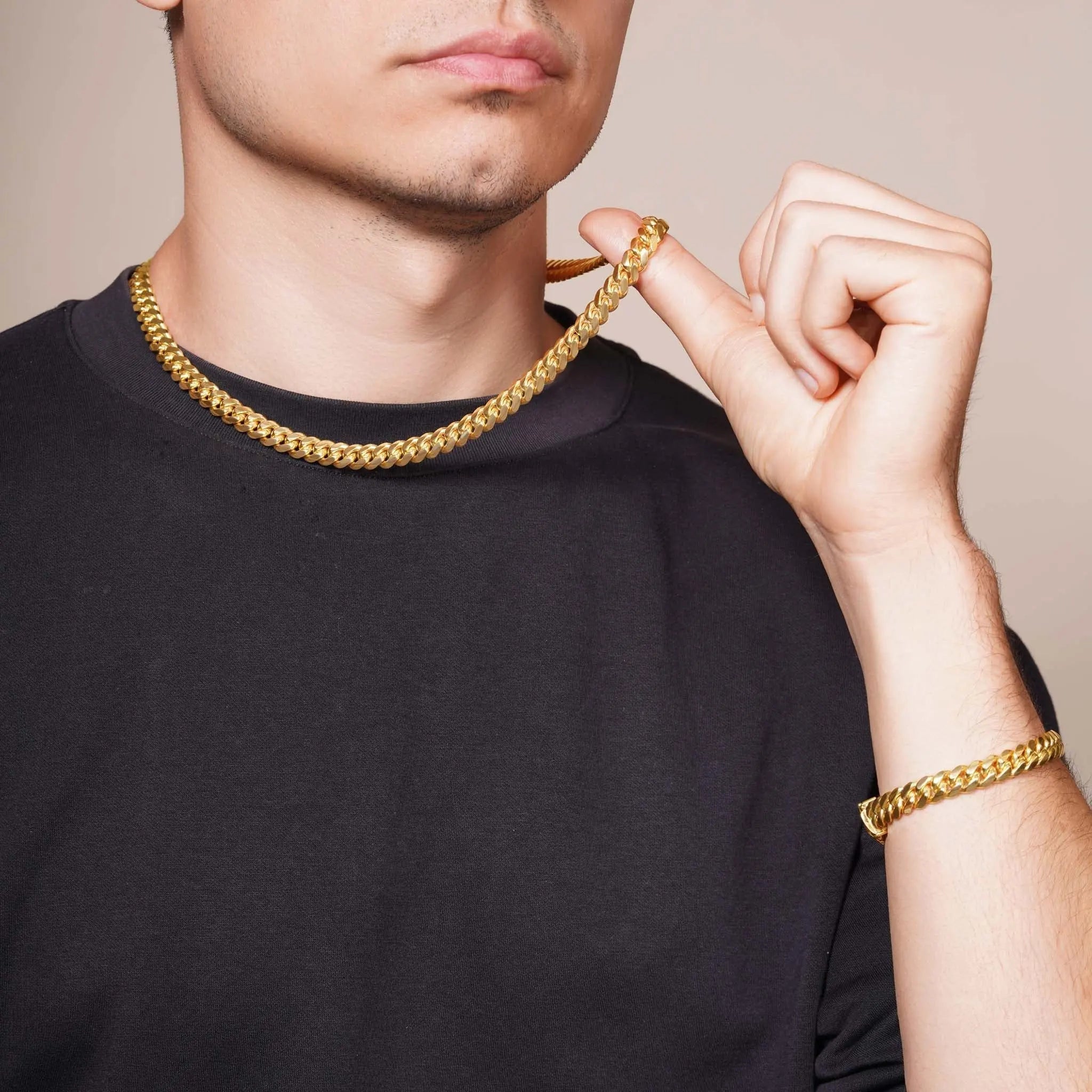 A man holding a gold chain and bracelet, showcasing gold jewelry as a stylish investment to consider when you Buy Gold.