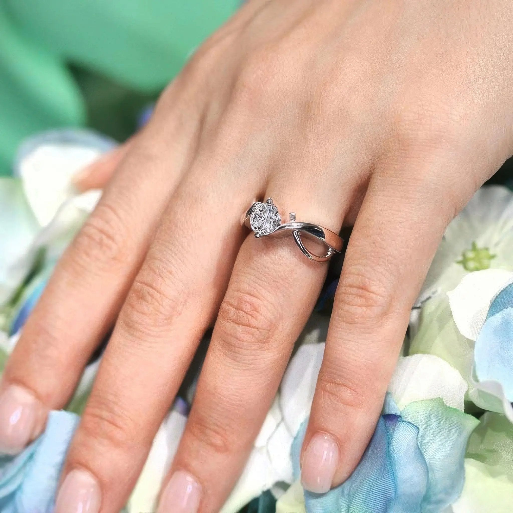 Double wire trim lab diamond solitaire ring on a hand, featuring a round center and curving shank design.