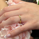 Sophia three stone promise ring shown on a hand, surrounded by pink flowers, featuring a bezel set diamond center.