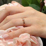 Hand wearing Aria princess cut diamond promise ring on a bed of pink roses, showcasing timeless elegance.
