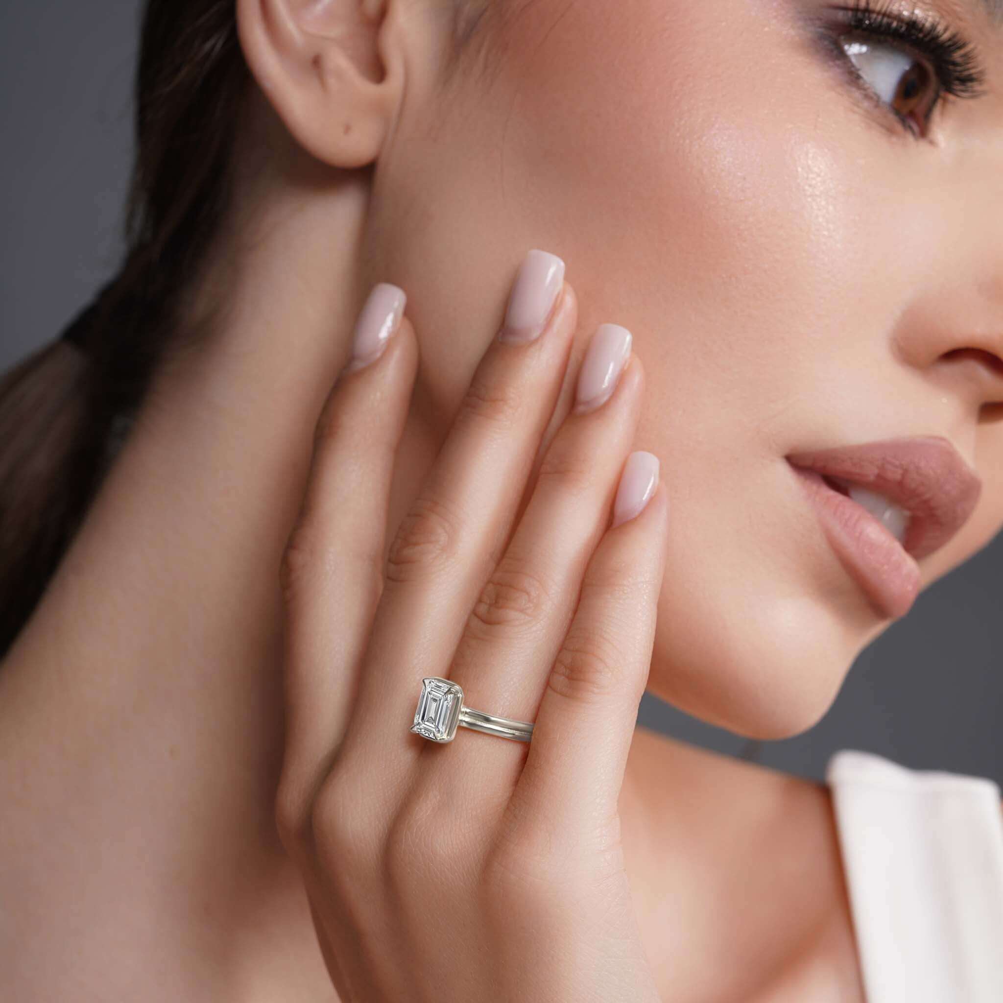 Close-up of a woman showcasing a Double Band 2 Carat Emerald Cut Diamond Solitaire Ring on her hand.