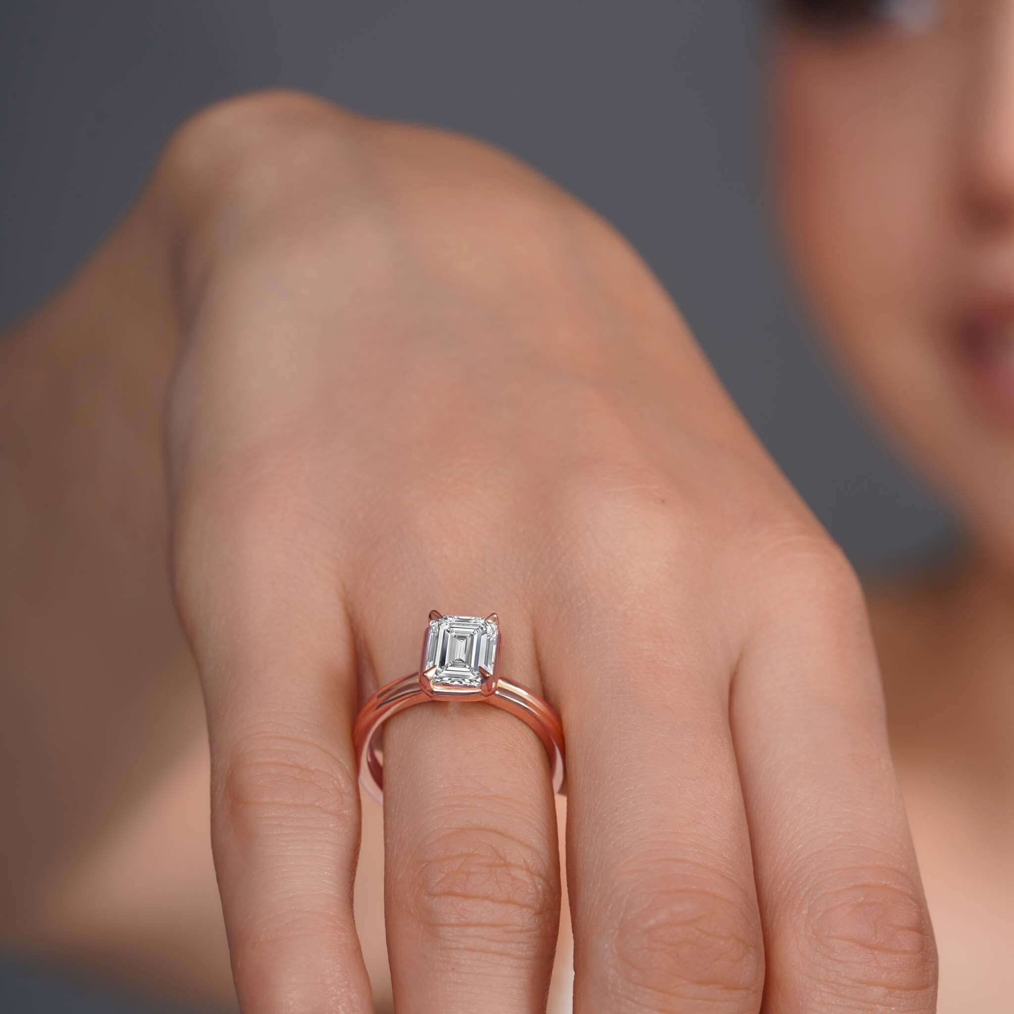 Double band 2 carat emerald cut diamond solitaire ring showcased on a hand, highlighting its elegant design and brilliance.