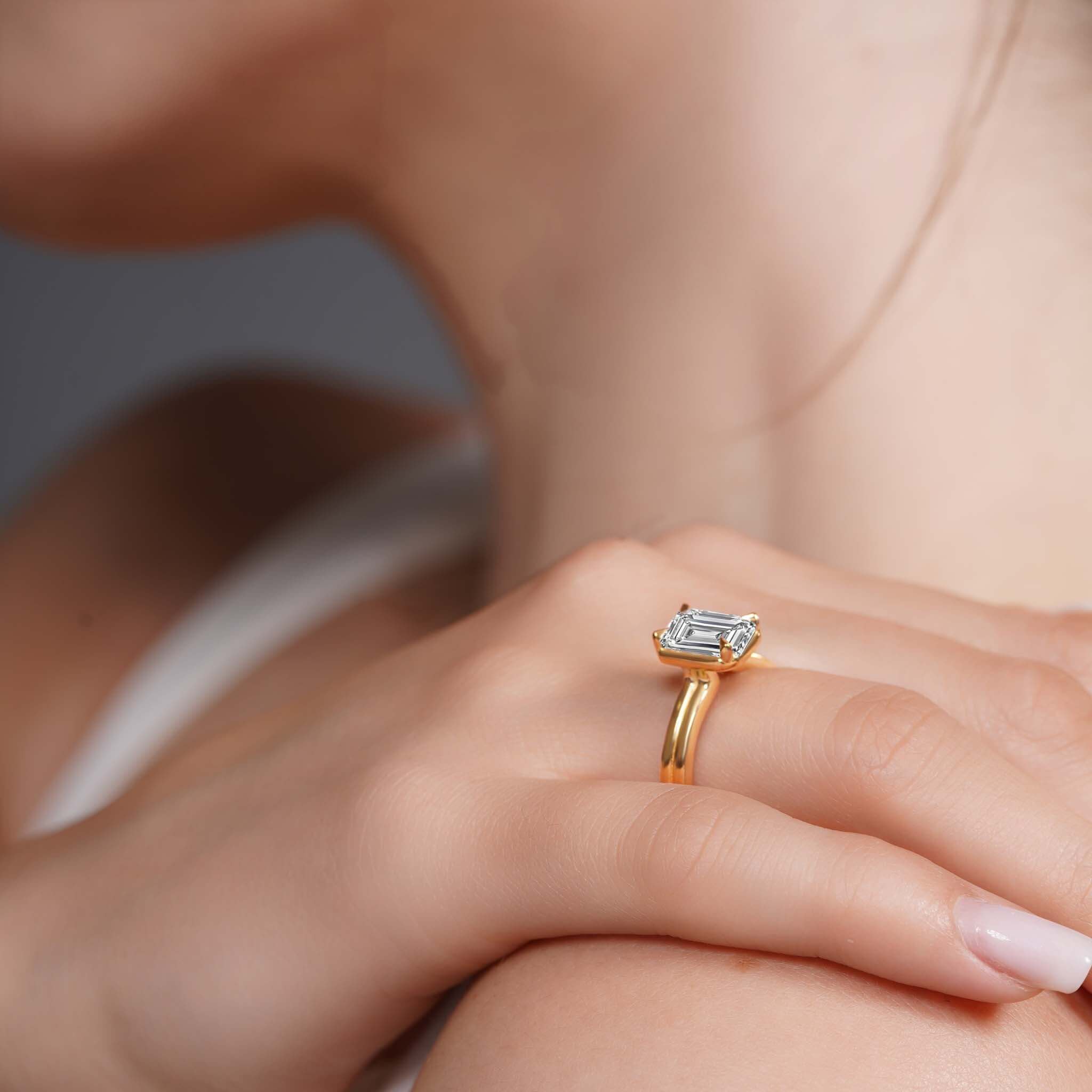 Elegant double band 2 carat emerald cut diamond solitaire ring worn on hand, showcasing refined sophistication.