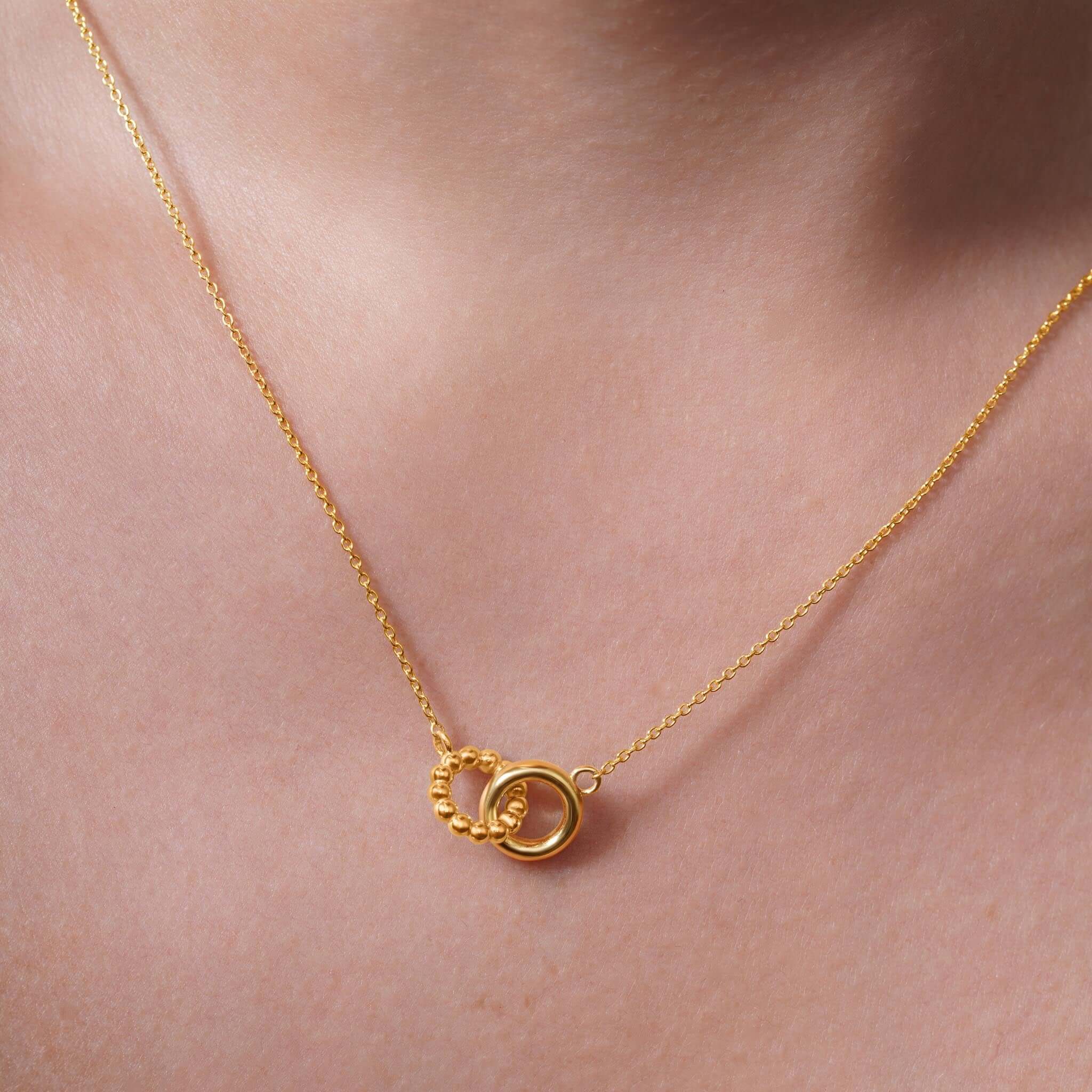Close-up of a Vermeil Double Circle Necklace featuring two intertwined circles on a model's neckline.