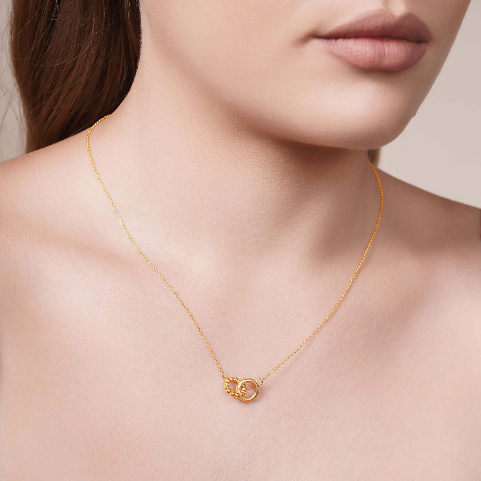 Gold Double Circle Necklace worn elegantly, featuring intertwined polished and beaded circles, showcasing refined style.