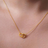Gold Double Circle Necklace featuring intertwined circles on a delicate chain, showcasing elegant design and versatility.