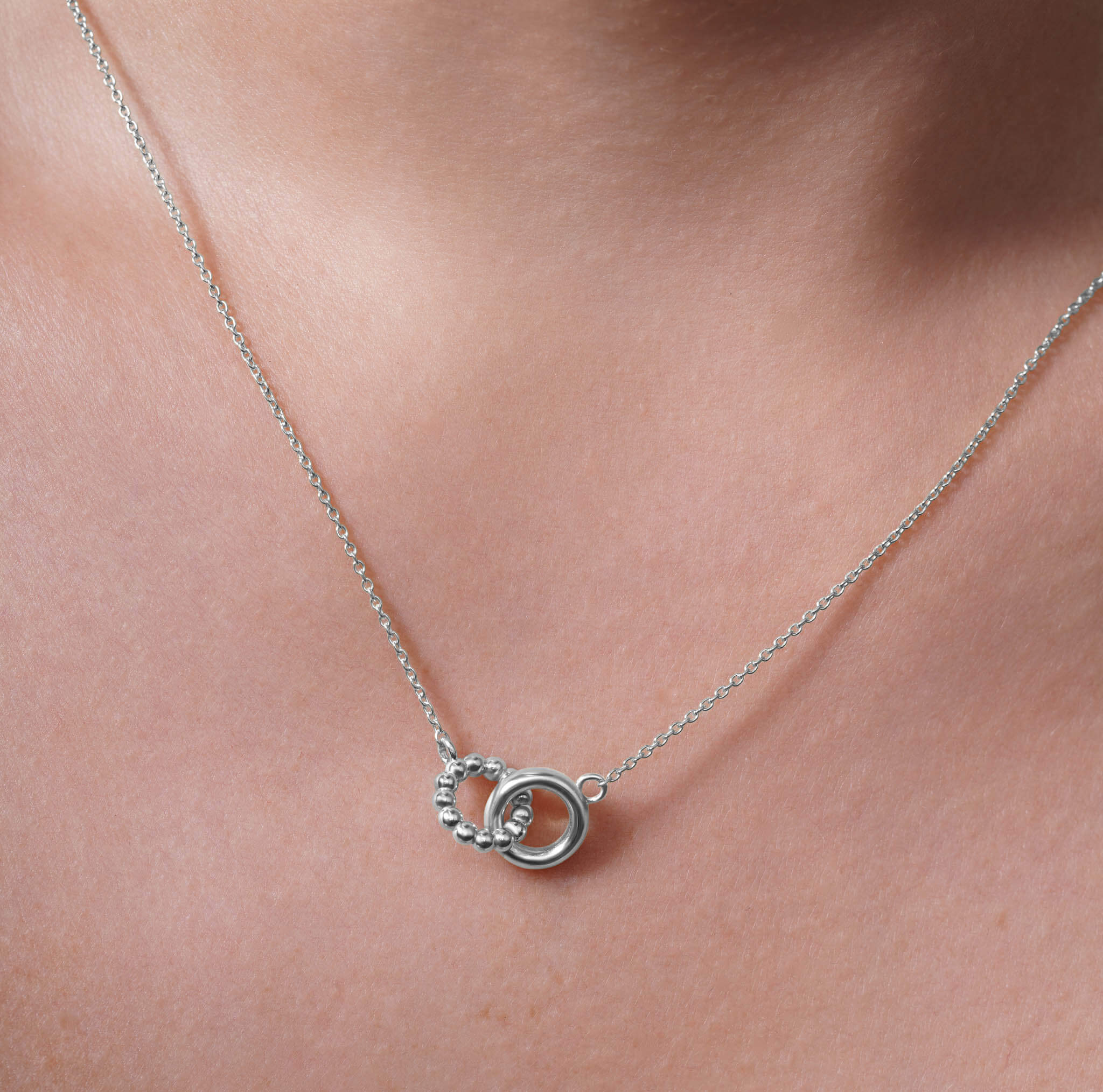 Gold Double Circle Necklace showcasing intertwined circles on a delicate chain, highlighting elegance and versatility.