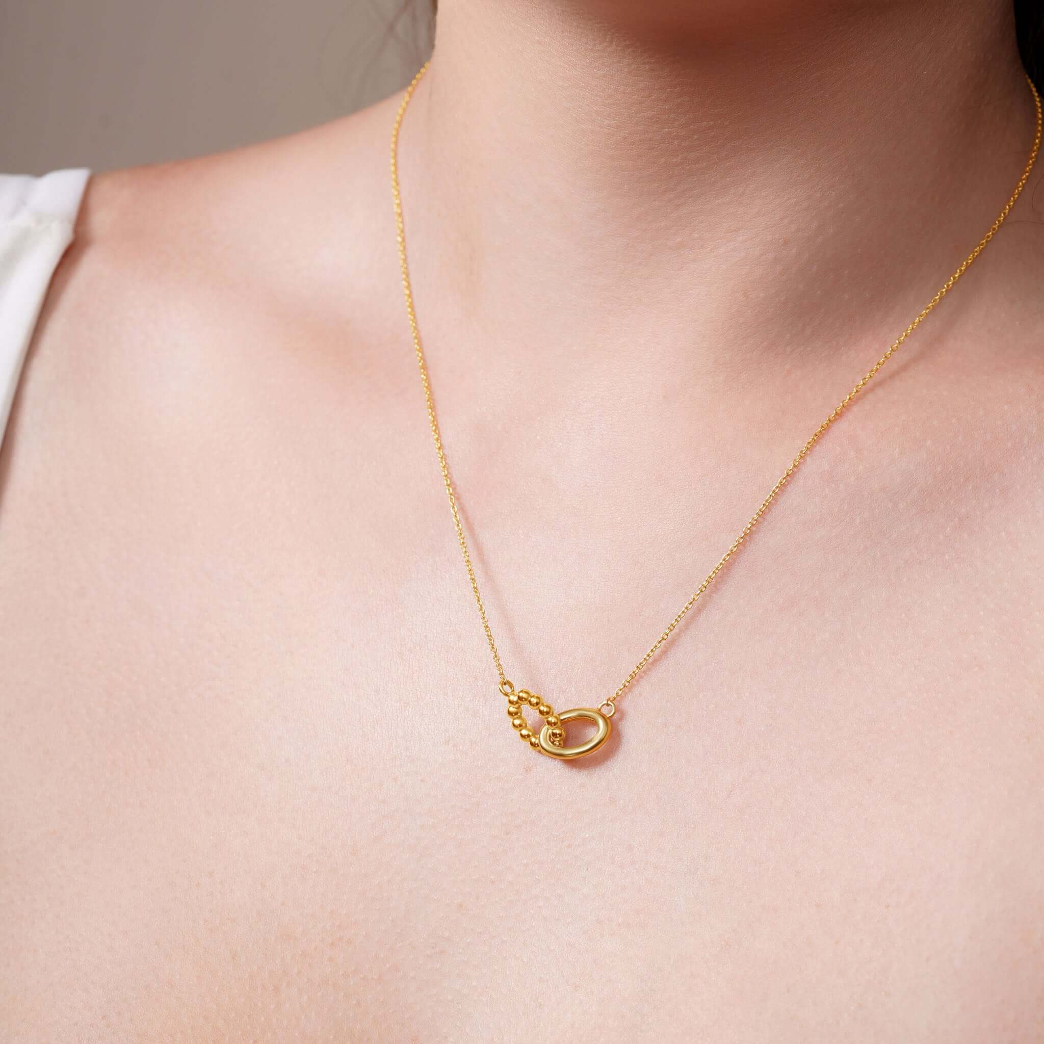 Close-up of a Vermeil Double Oval Necklace featuring intertwined oval shapes and a delicate chain, ideal for elegant styling.