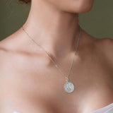 Close-up of a woman wearing a Zodiac Necklace with a silver medallion and sleek bar chain, highlighting her star sign.