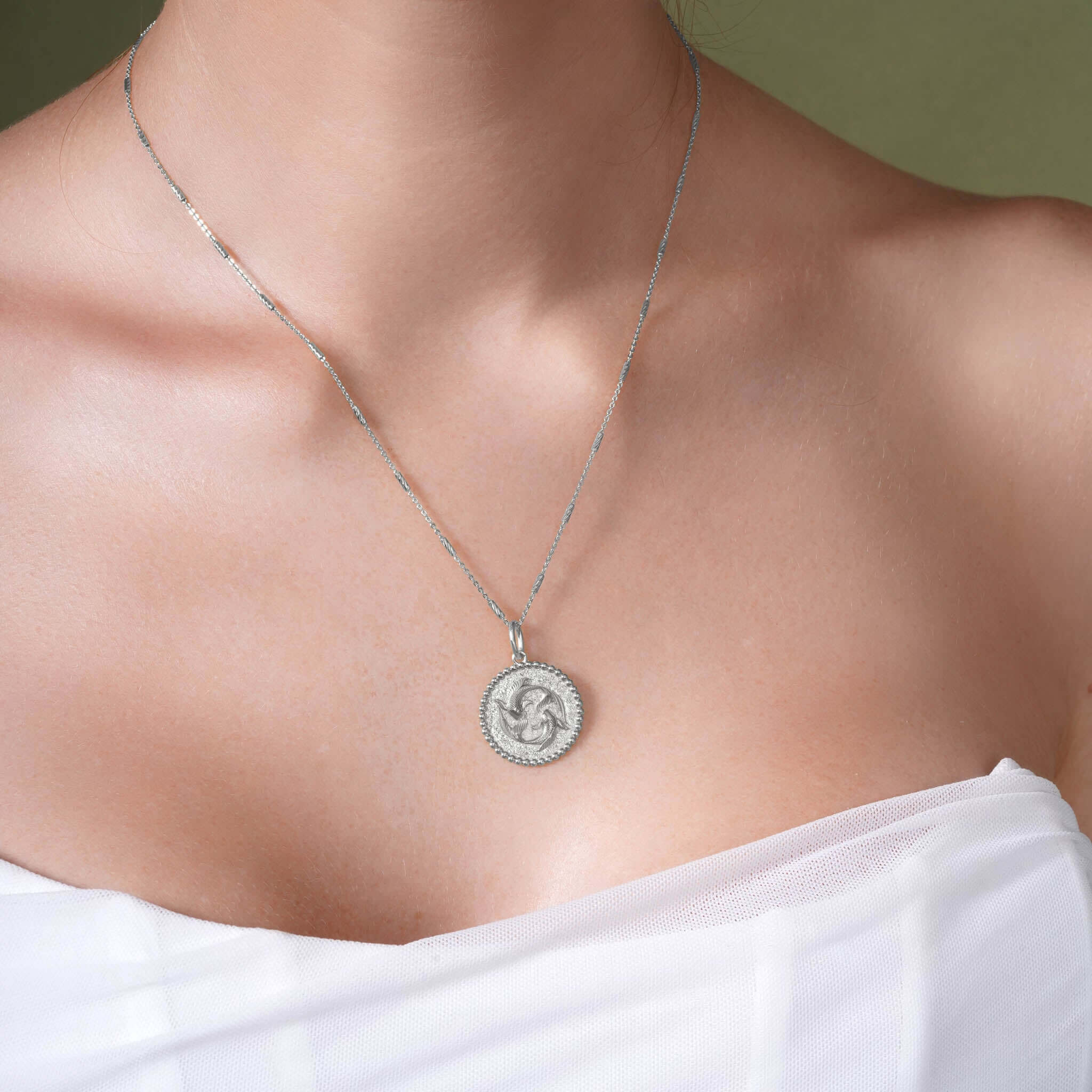 Close-up of a woman wearing a Zodiac Necklace featuring a circular medallion with intricate design.