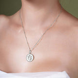 Zodiac Necklace featuring a medallion with a textured background, worn on a sleek bar chain.