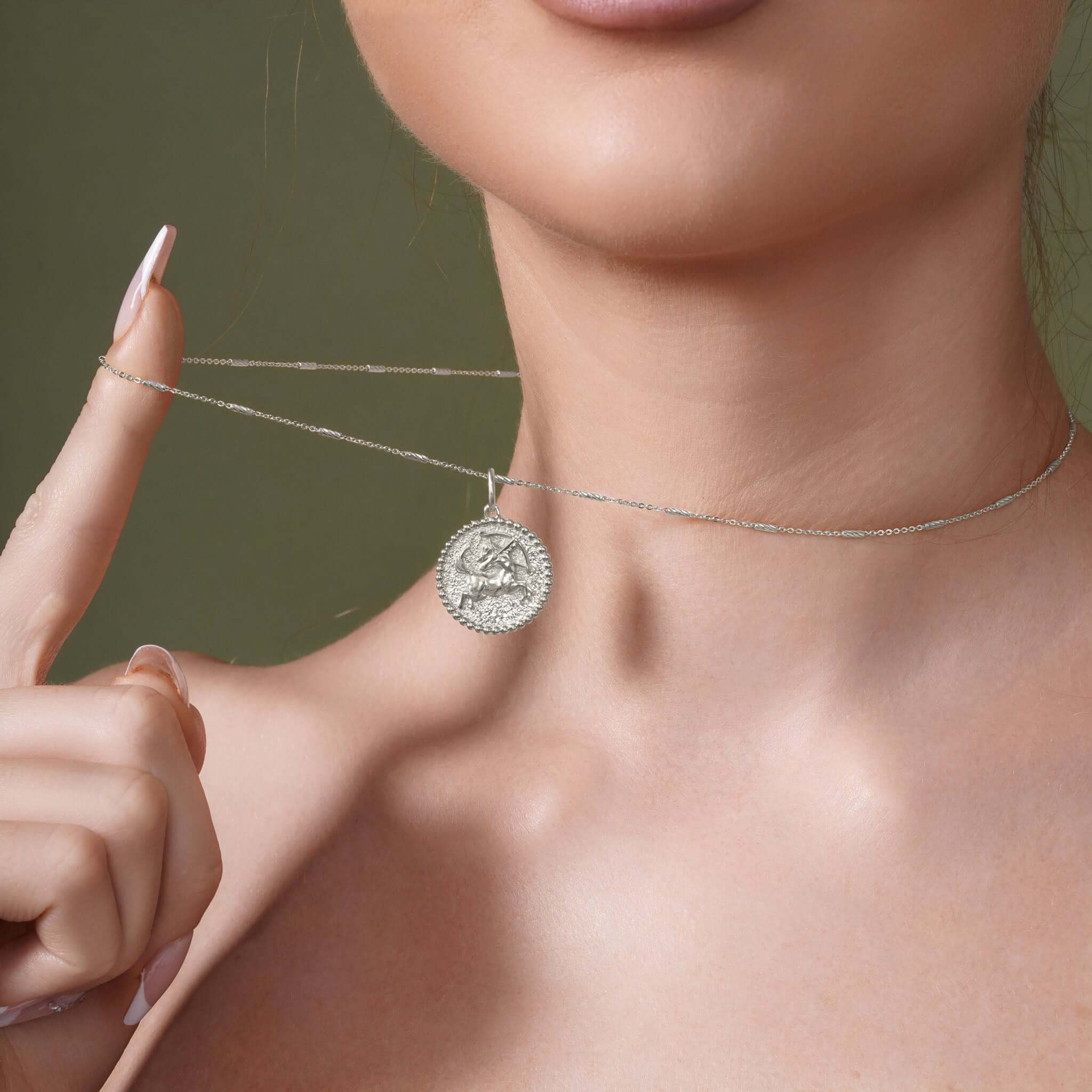 Close-up of a woman wearing a Zodiac Necklace, featuring a medallion with a zodiac symbol on a sleek chain.