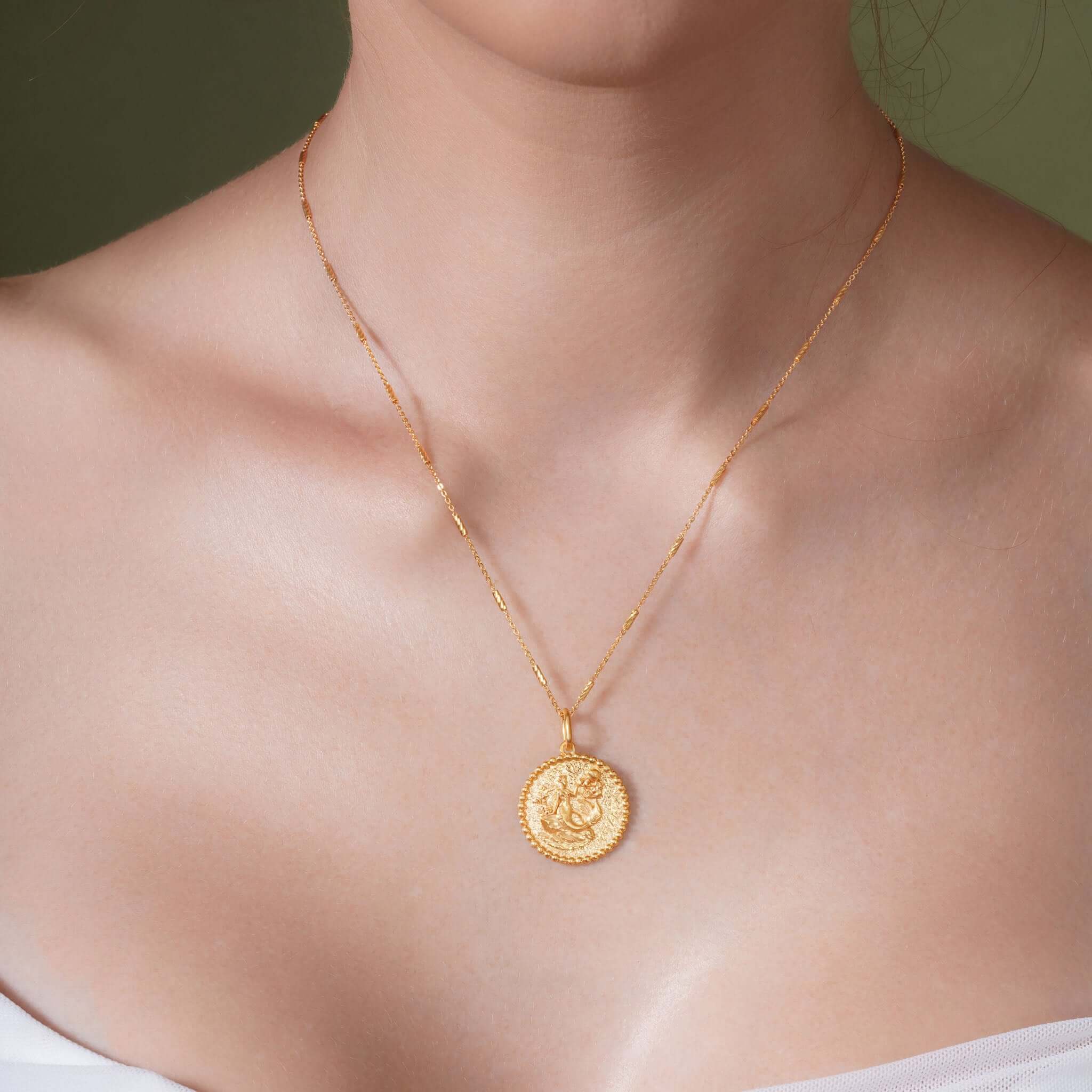Model wearing a Zodiac Necklace with a medallion style pendant and delicate gold bar chain.