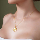 Zodiac Necklace featuring a gold medallion with zodiac symbol on a woman, showcasing its elegant design and adjustable chain.
