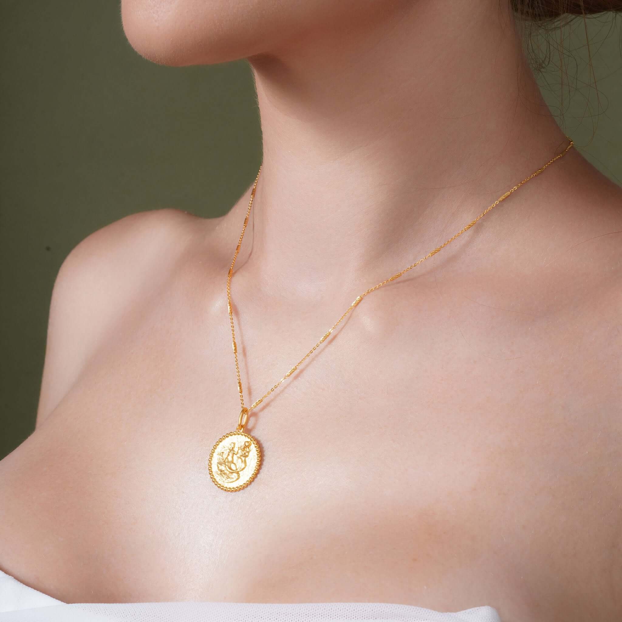 Zodiac Necklace featuring a gold medallion with zodiac symbol on a woman, showcasing its elegant design and adjustable chain.