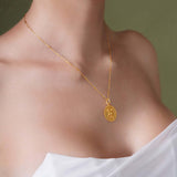 Zodiac Necklace displayed on a model's neck featuring a gold medallion and delicate chain.