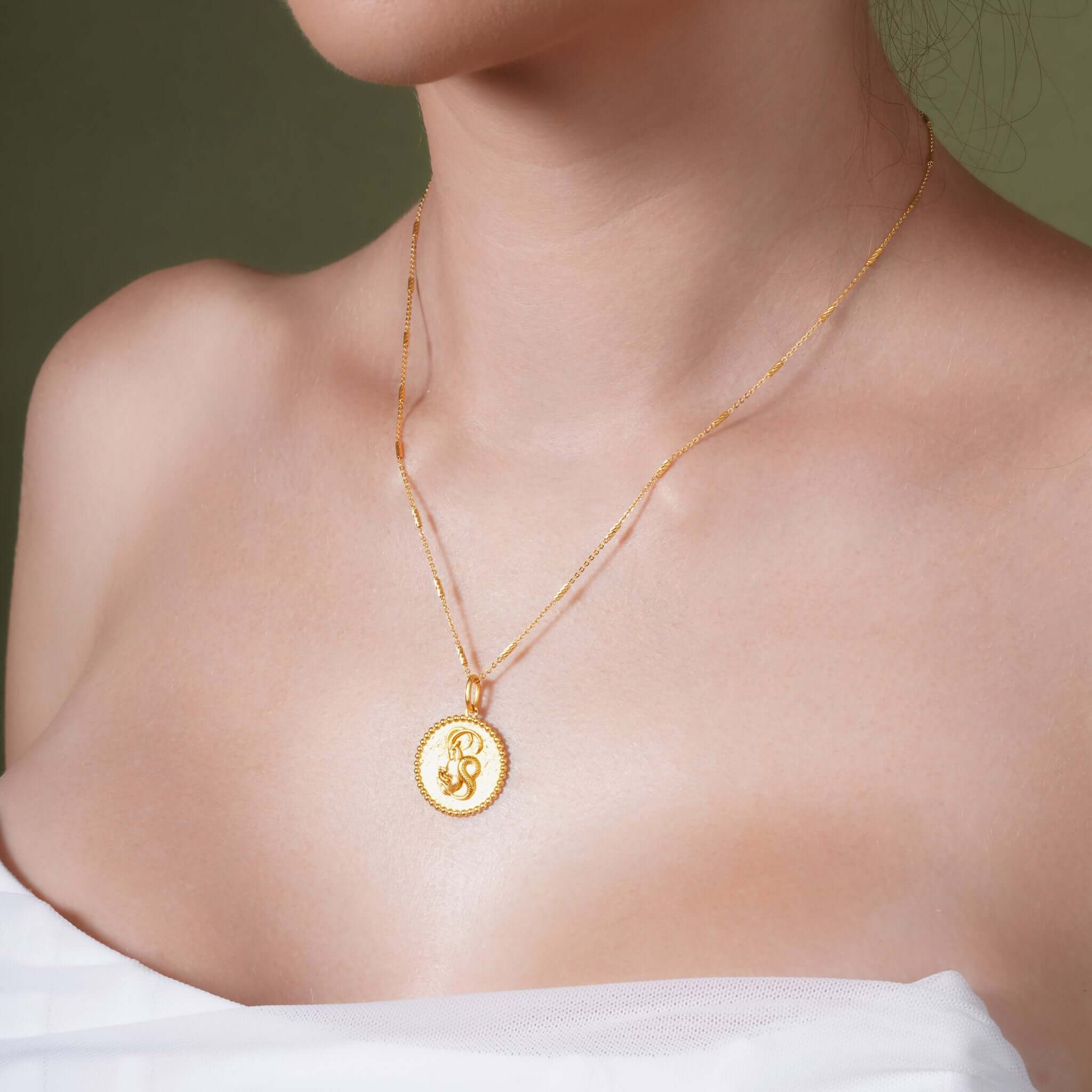 Zodiac Necklace displayed on a model, featuring a gold medallion with a zodiac symbol and delicate chain.