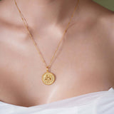 Zodiac Necklace showcasing gold medallion with zodiac symbol, worn on a sleek chain against a textured background.