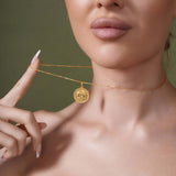 Zodiac Necklace featuring a gold medallion pendant on a sleek chain worn close to the neckline.