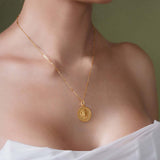 Woman wearing a gold Zodiac Necklace with a medallion pendant on a delicate chain.