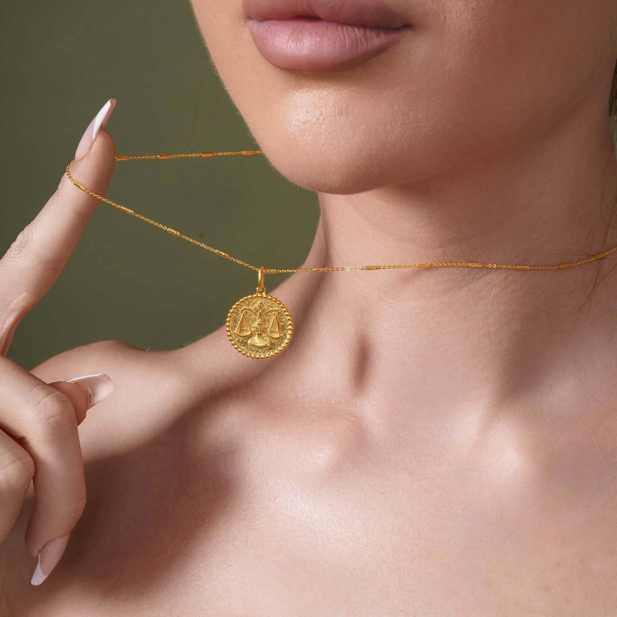 Zodiac Necklace featuring a gold medallion symbol on a delicate chain worn close to the neckline.