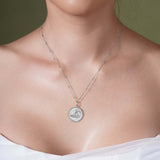 Zodiac Necklace featuring a medallion style pendant on sleek bar chain, worn close to the neckline.
