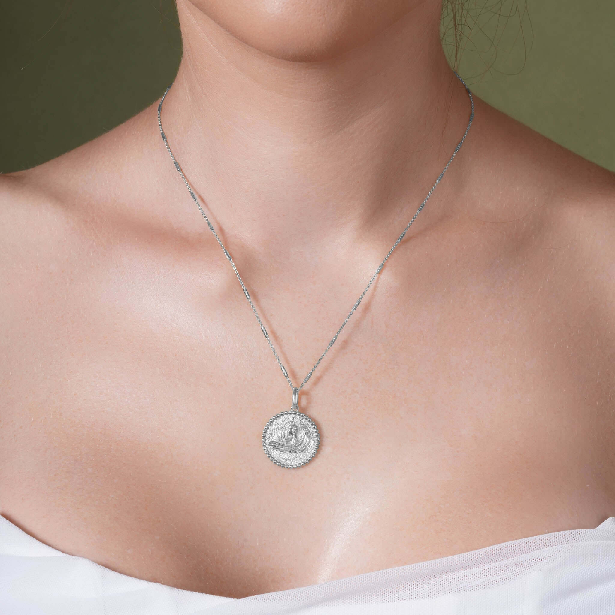 Zodiac Necklace featuring a medallion style pendant on sleek bar chain, worn close to the neckline.