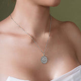 Close-up of a woman wearing a Zodiac Necklace with a textured medallion and sleek chain.