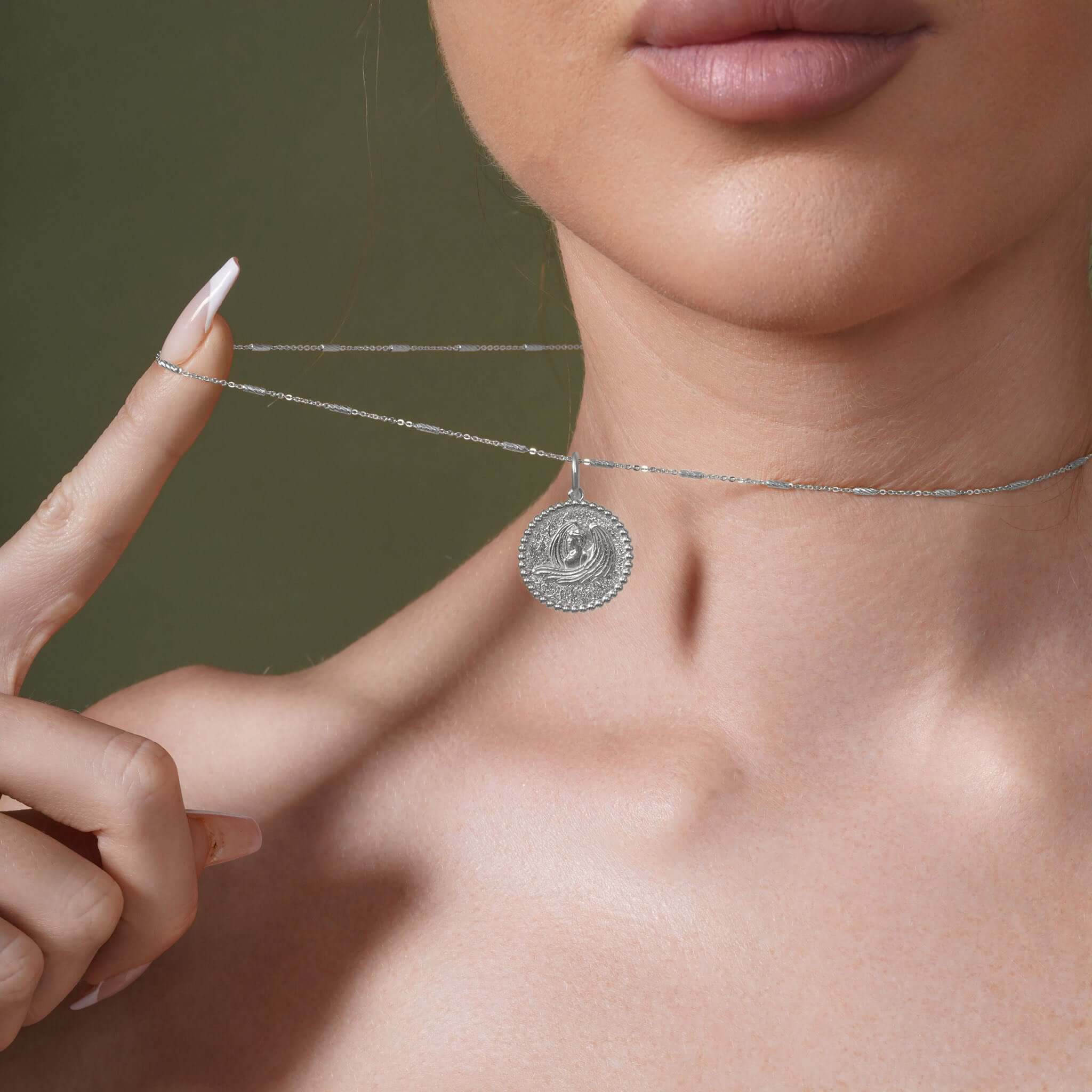 Zodiac Necklace featuring a textured medallion symbol, set on a sleek chain worn close to the neckline.