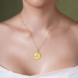Zodiac Necklace showcasing a gold medallion with a zodiac symbol on a sleek bar chain worn close to the neckline.