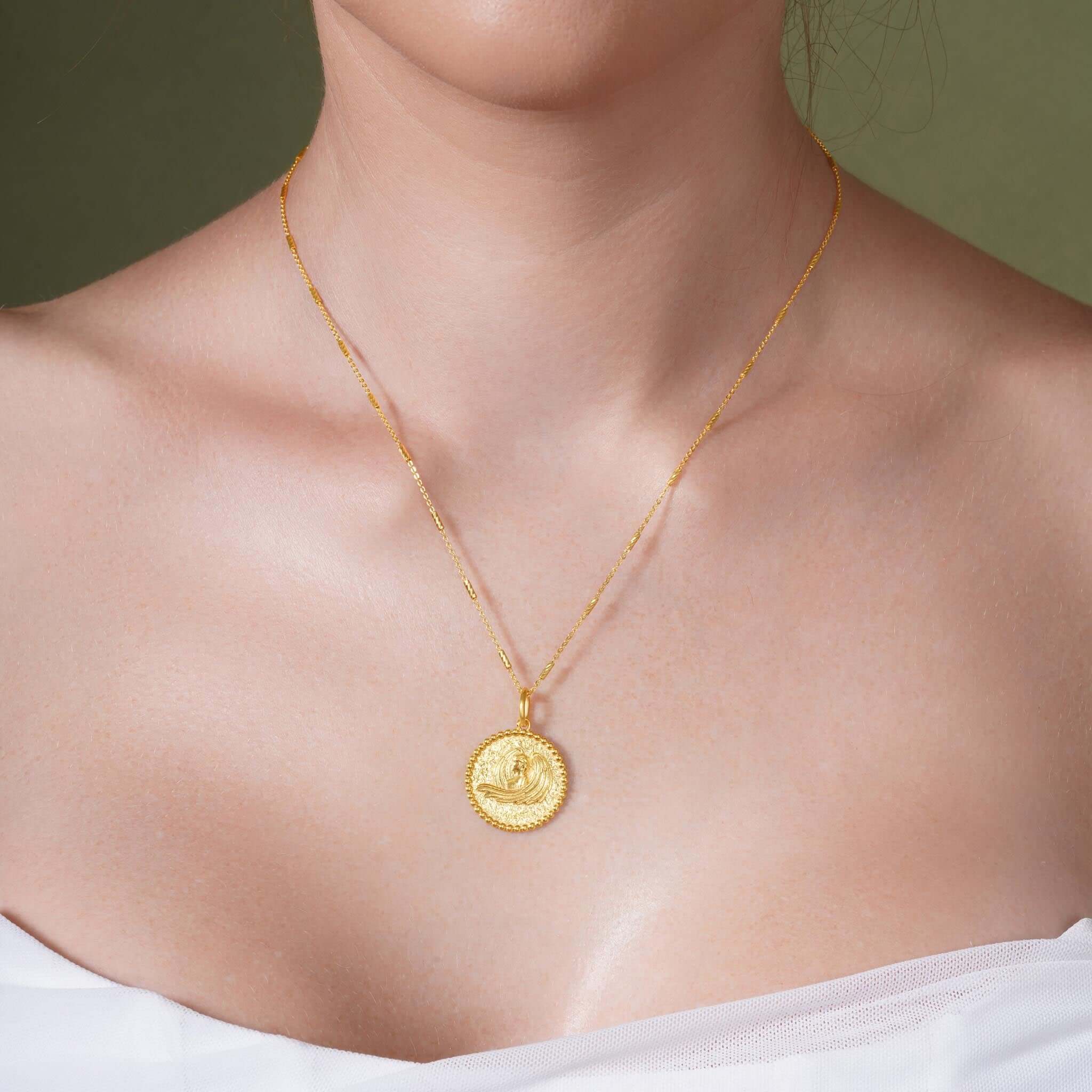 Zodiac Necklace showcasing a gold medallion with a zodiac symbol on a sleek bar chain worn close to the neckline.