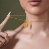 Zodiac Necklace worn close to neckline, showcasing zodiac symbol medallion with textured background.