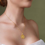 Zodiac Necklace featuring a gold medallion with a textured background, worn on a sleek bar chain.