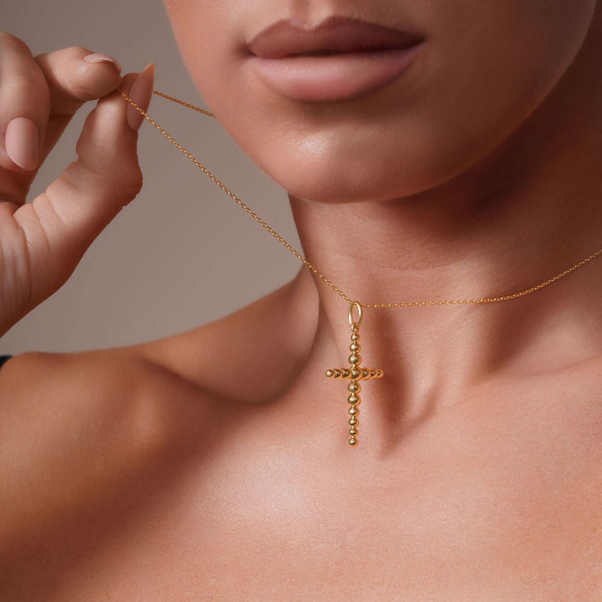 Vermeil Beaded Cross Necklace displayed on a model, showcasing its polished bead-shaped cross and adjustable chain.
