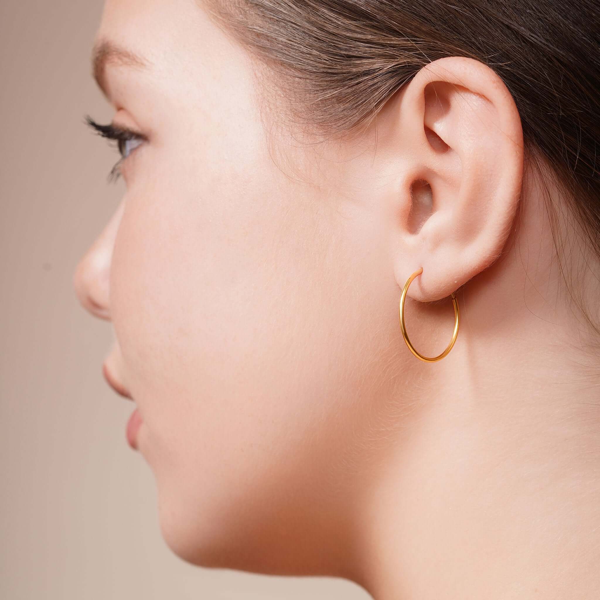 Side profile of a woman wearing Gold Endless Hoop Earrings, showcasing their elegant design and shine.