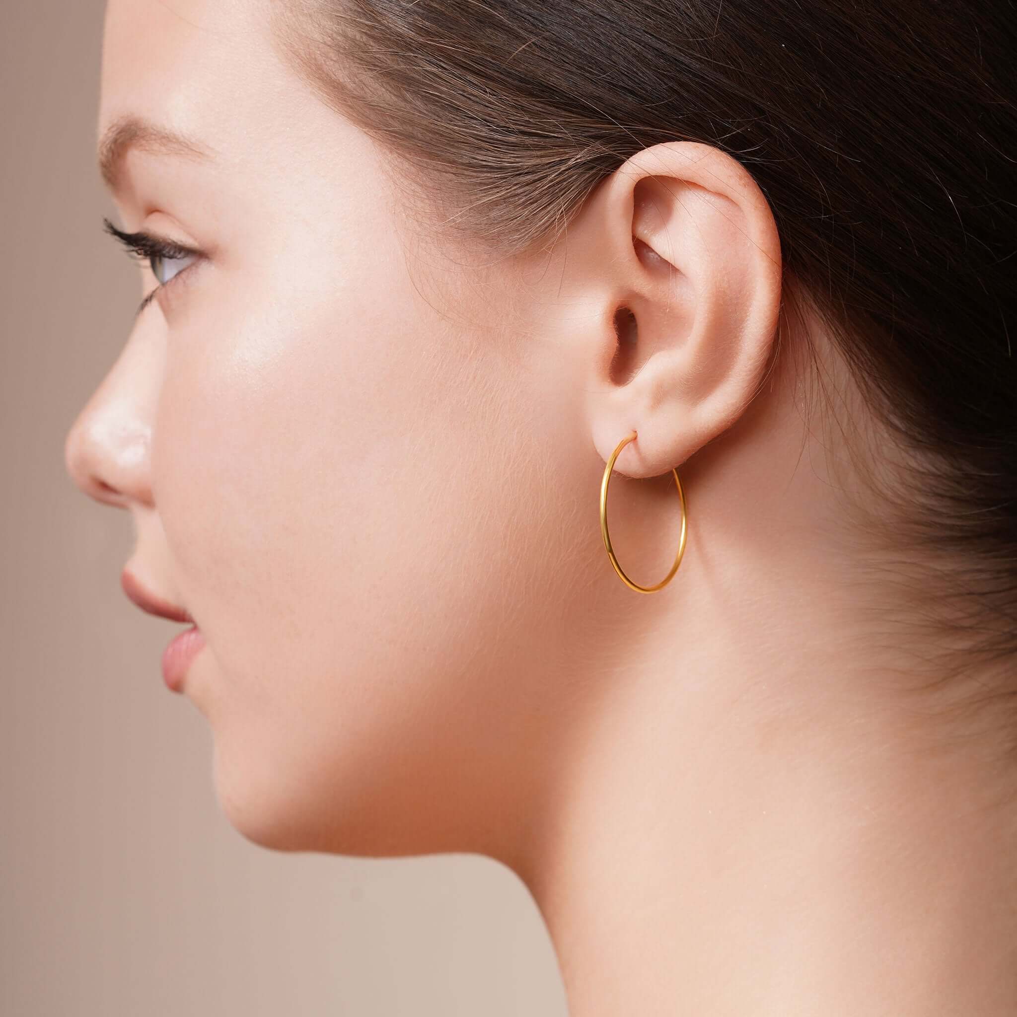 Gold Endless Hoop Earrings worn by a model, showcasing their timeless design and elegant shape.