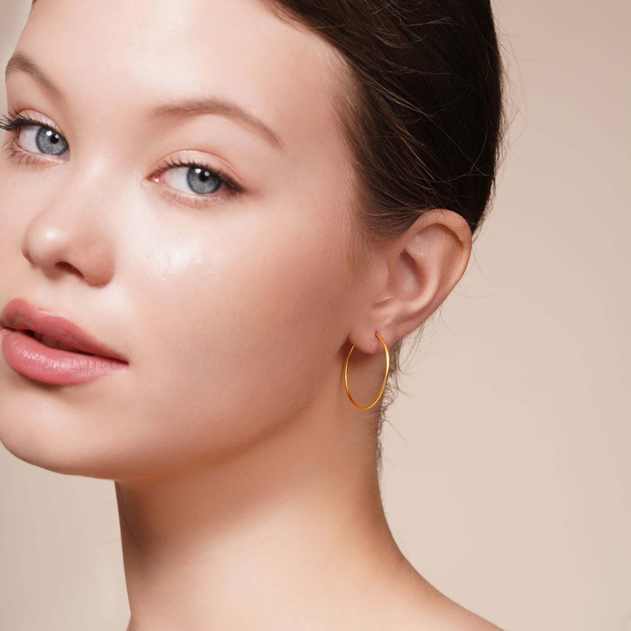 Close-up of a model wearing Gold Endless Hoop Earrings, showcasing their elegant design and gold finish.