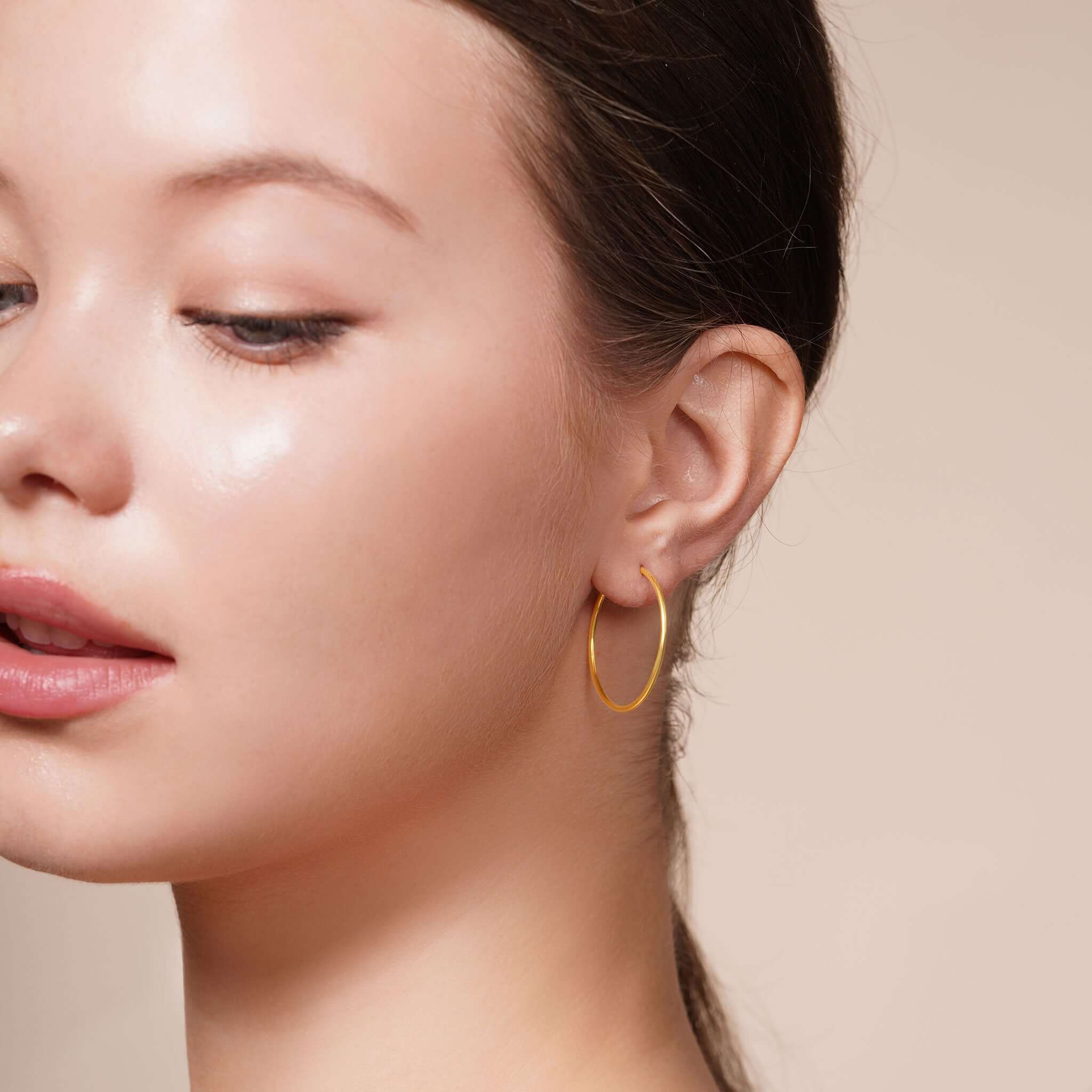 Gold Endless Hoop Earrings worn by a woman, showcasing timeless elegance and shine.