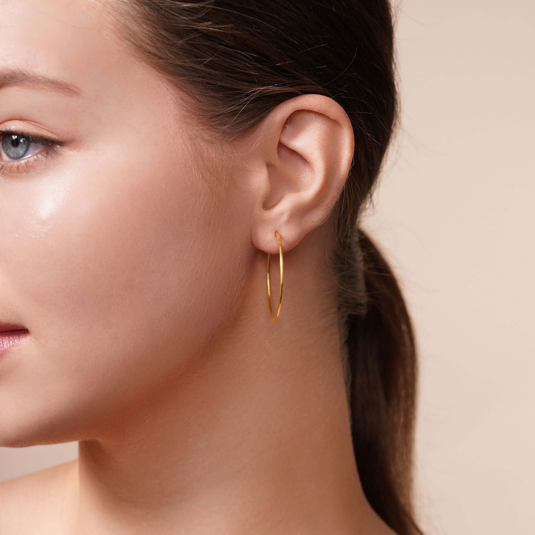 Woman wearing Gold Endless Hoop Earrings, showcasing timeless design and elegance for any occasion.