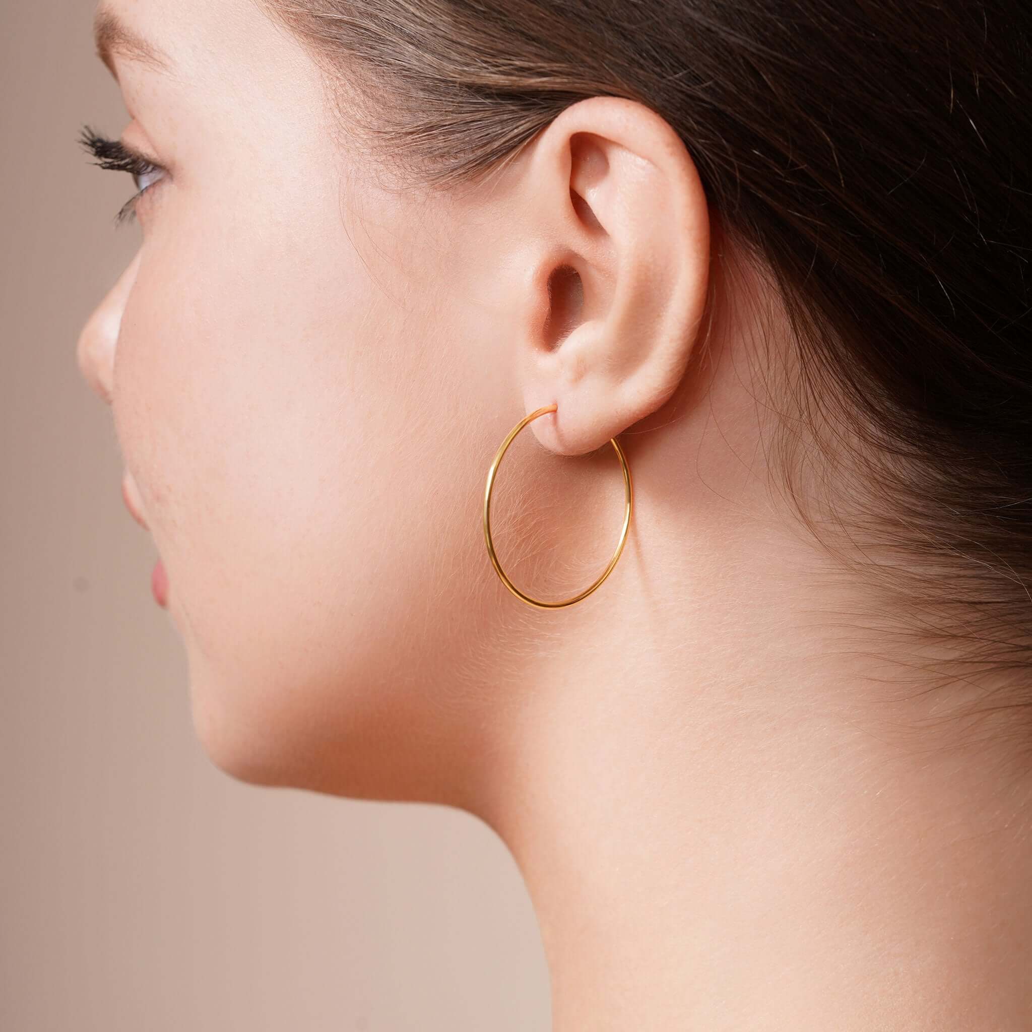 Model wearing Gold Endless Hoop Earrings highlighting timeless elegance and durability.