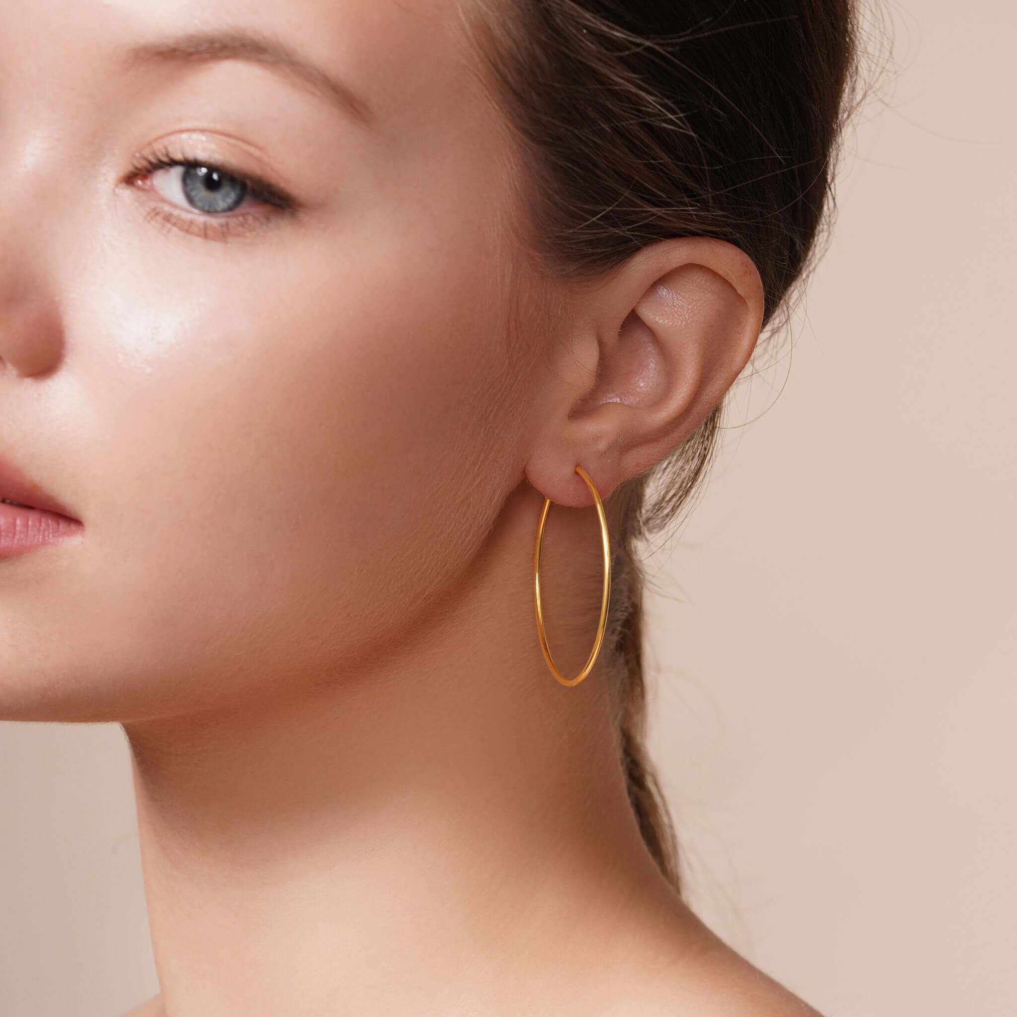 Close-up of a model wearing Gold Endless Hoop Earrings, showcasing their elegant design and shine.