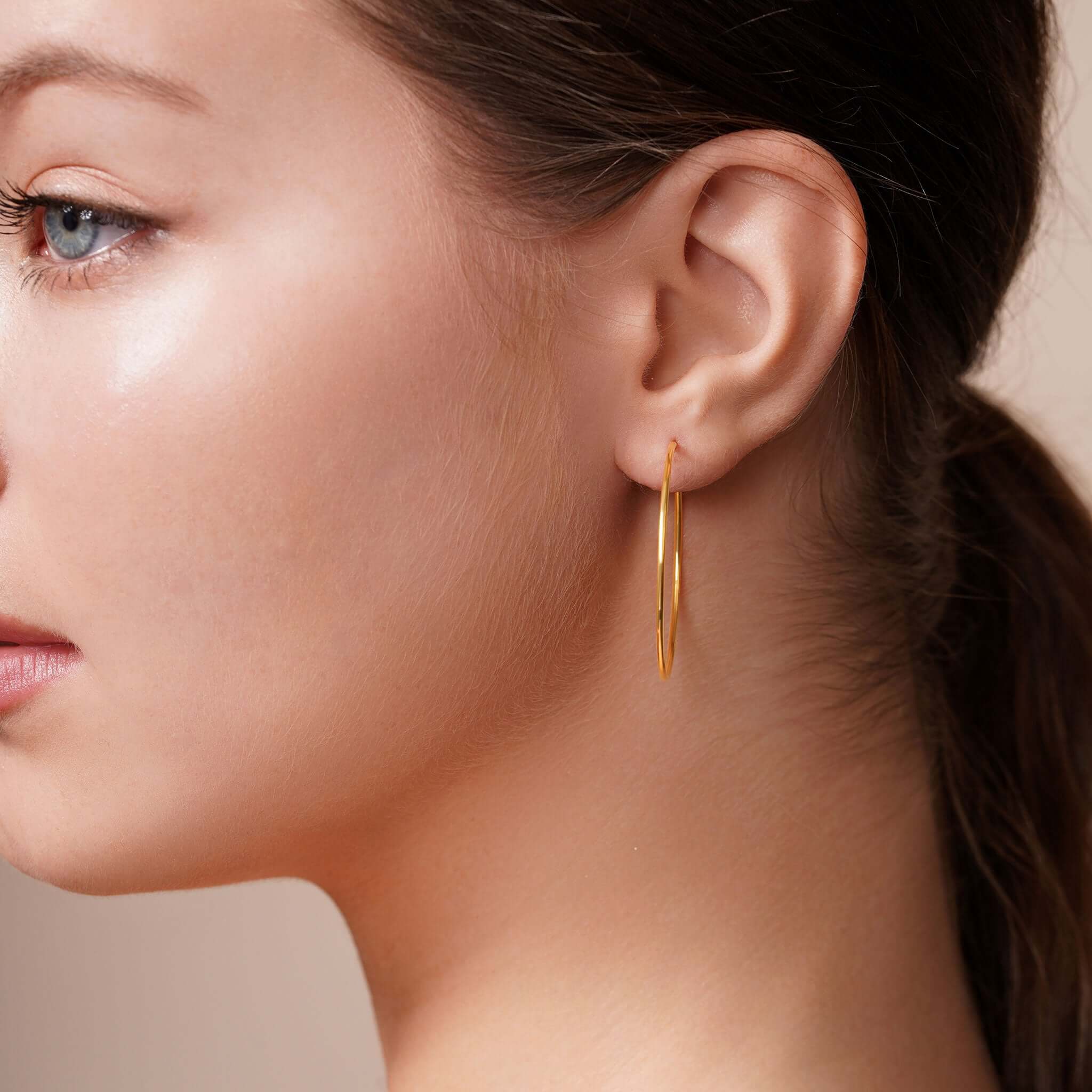 Gold Endless Hoop Earrings showcased on model's ear, highlighting timeless design and elegant style.