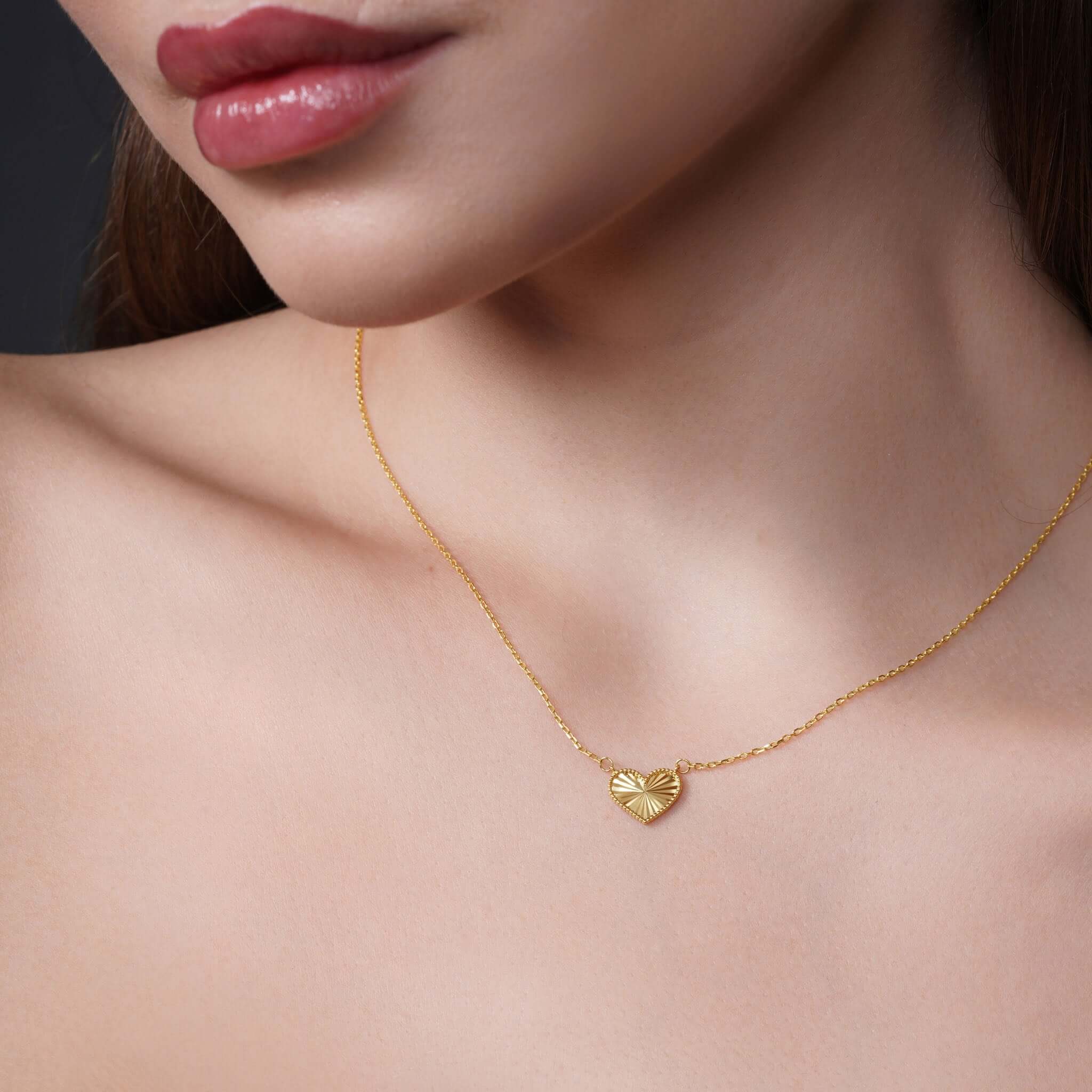 Engraved Heart Necklace worn by a model, showcasing the intricate heart-shaped pendant in yellow gold.