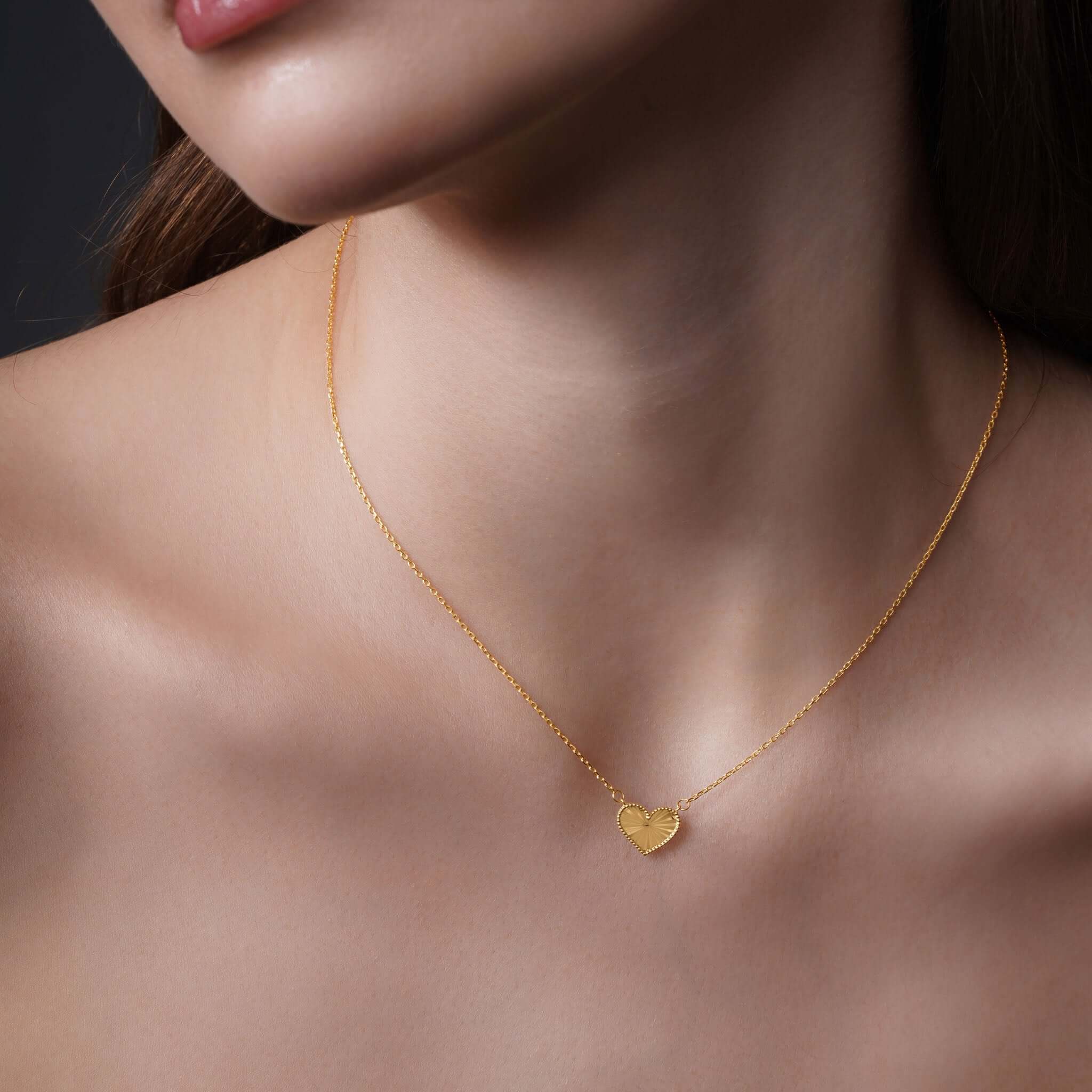 Engraved Heart Necklace displayed on model, featuring a textured heart pendant in 14k yellow gold.