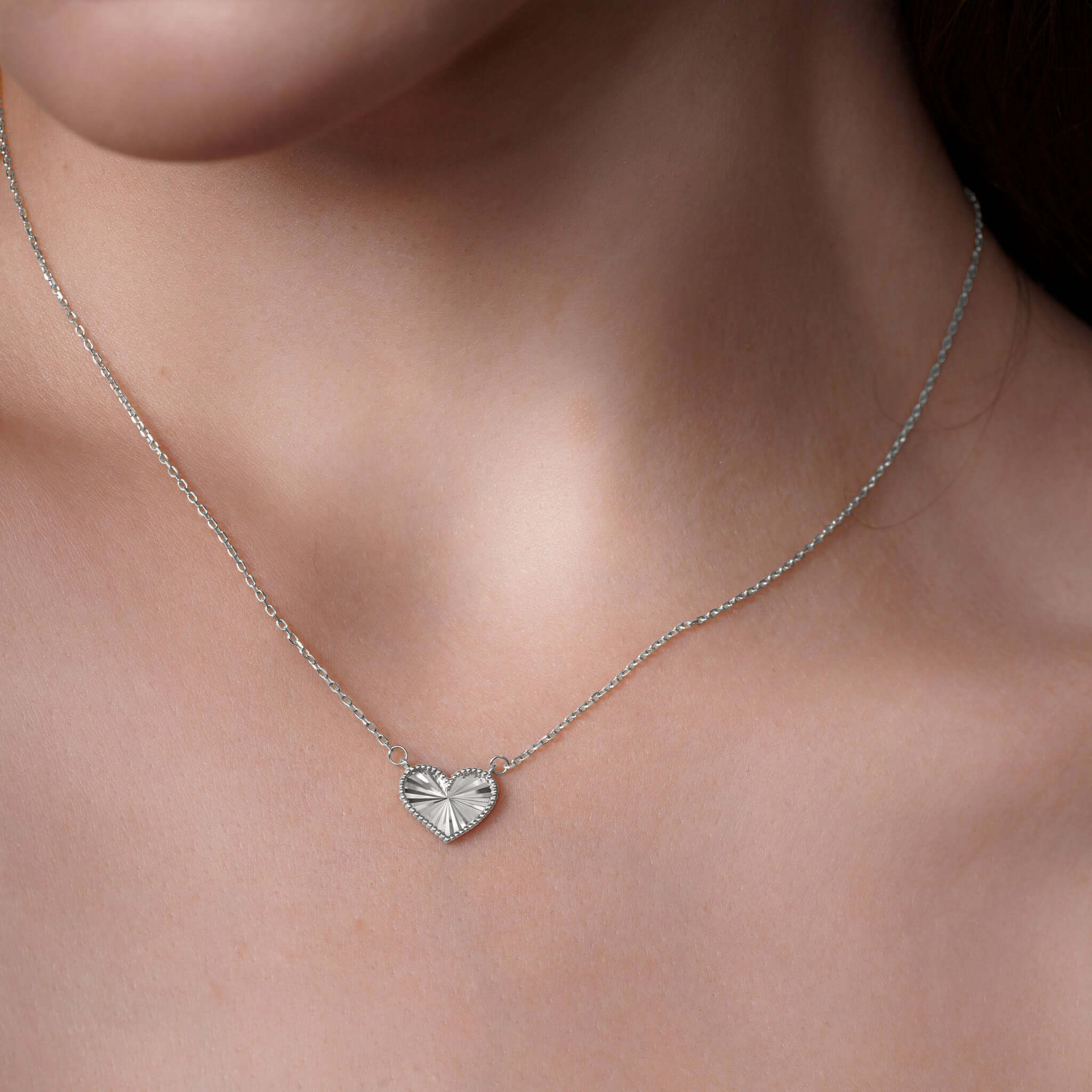 Engraved Heart Necklace showcased on a model, highlighting its textured heart-shaped pendant in silver.