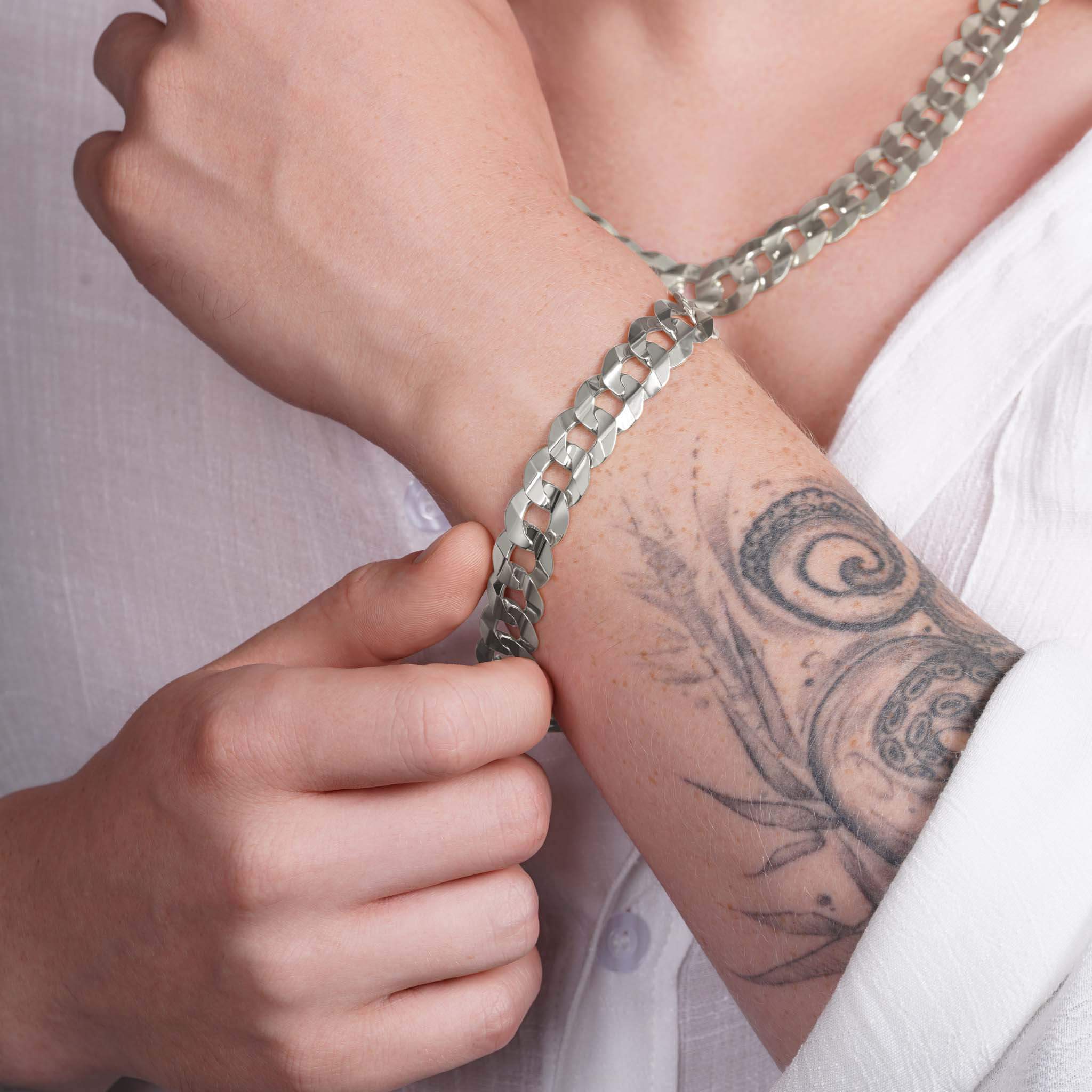 Men's solid gold curb bracelet worn on a wrist with a tattoo, showcasing durability and style.