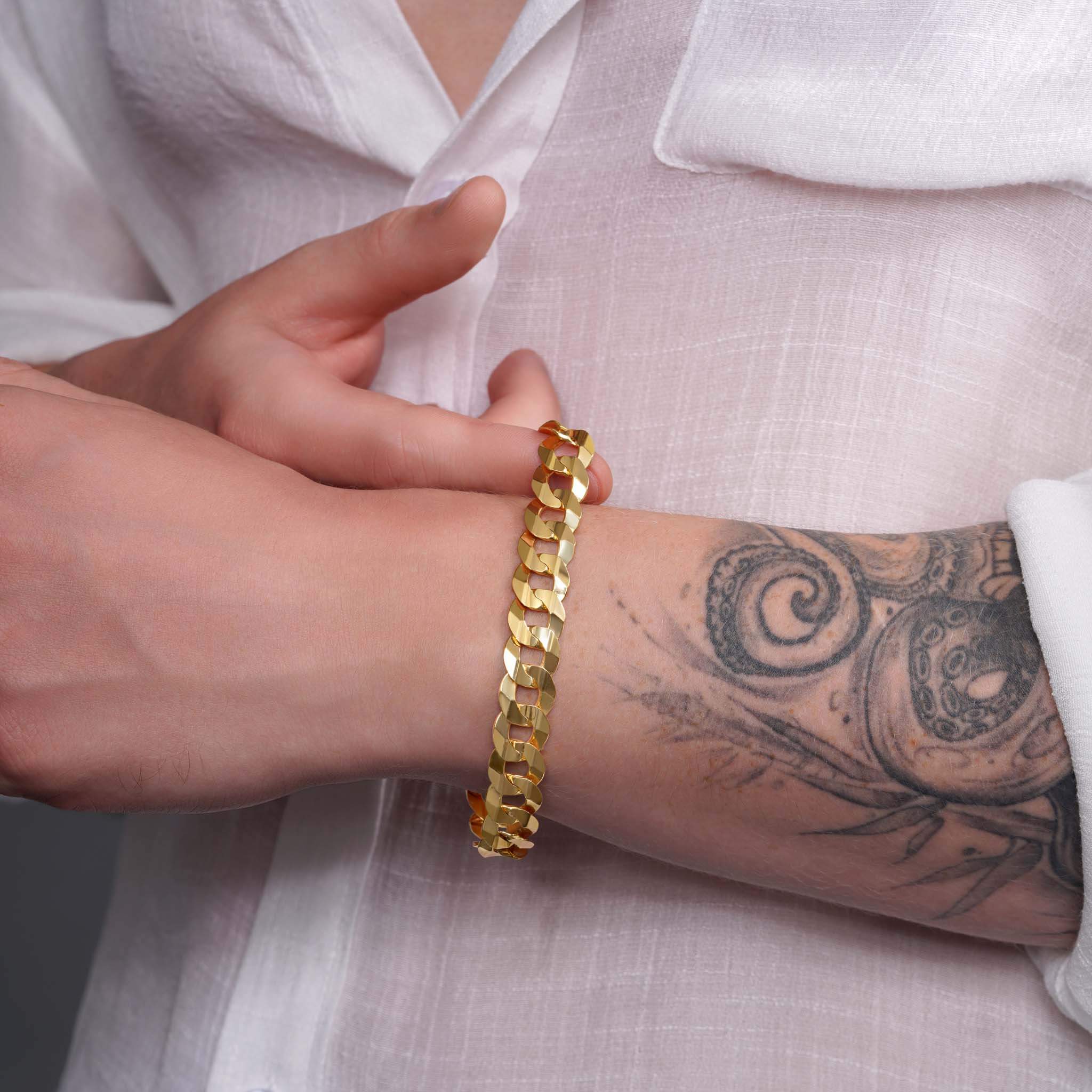 Men's 14K solid gold curb bracelet worn on a hand, showcasing its sleek design and craftsmanship.