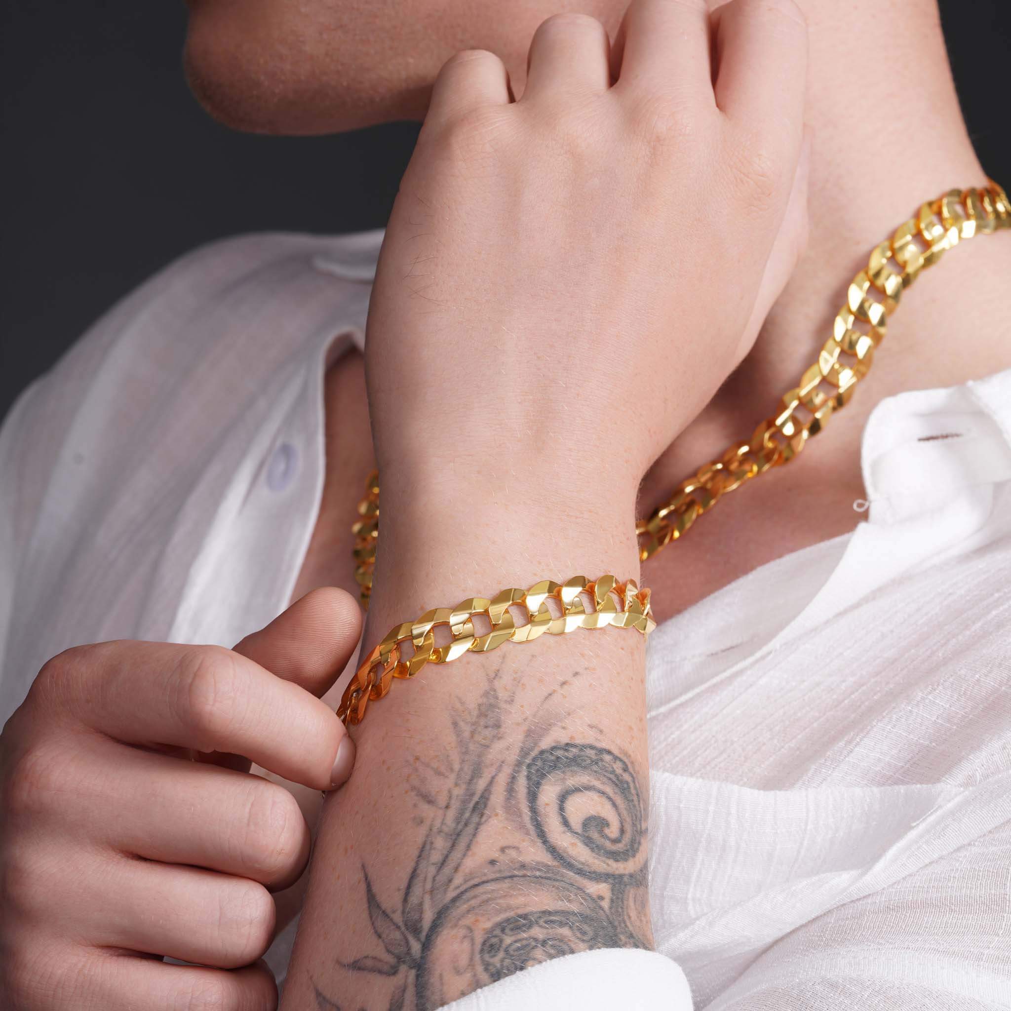 Close-up of a model wearing a men's solid gold curb bracelet, showcasing the elegant design and craftsmanship.
