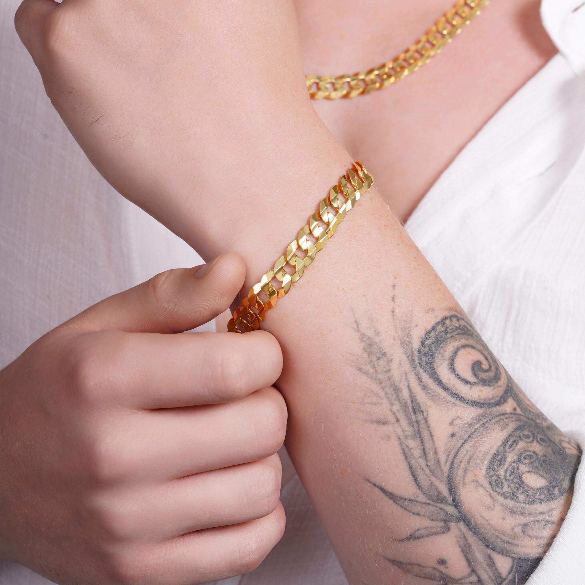Model wearing a men's solid gold curb bracelet showcasing its classic design and elegance.