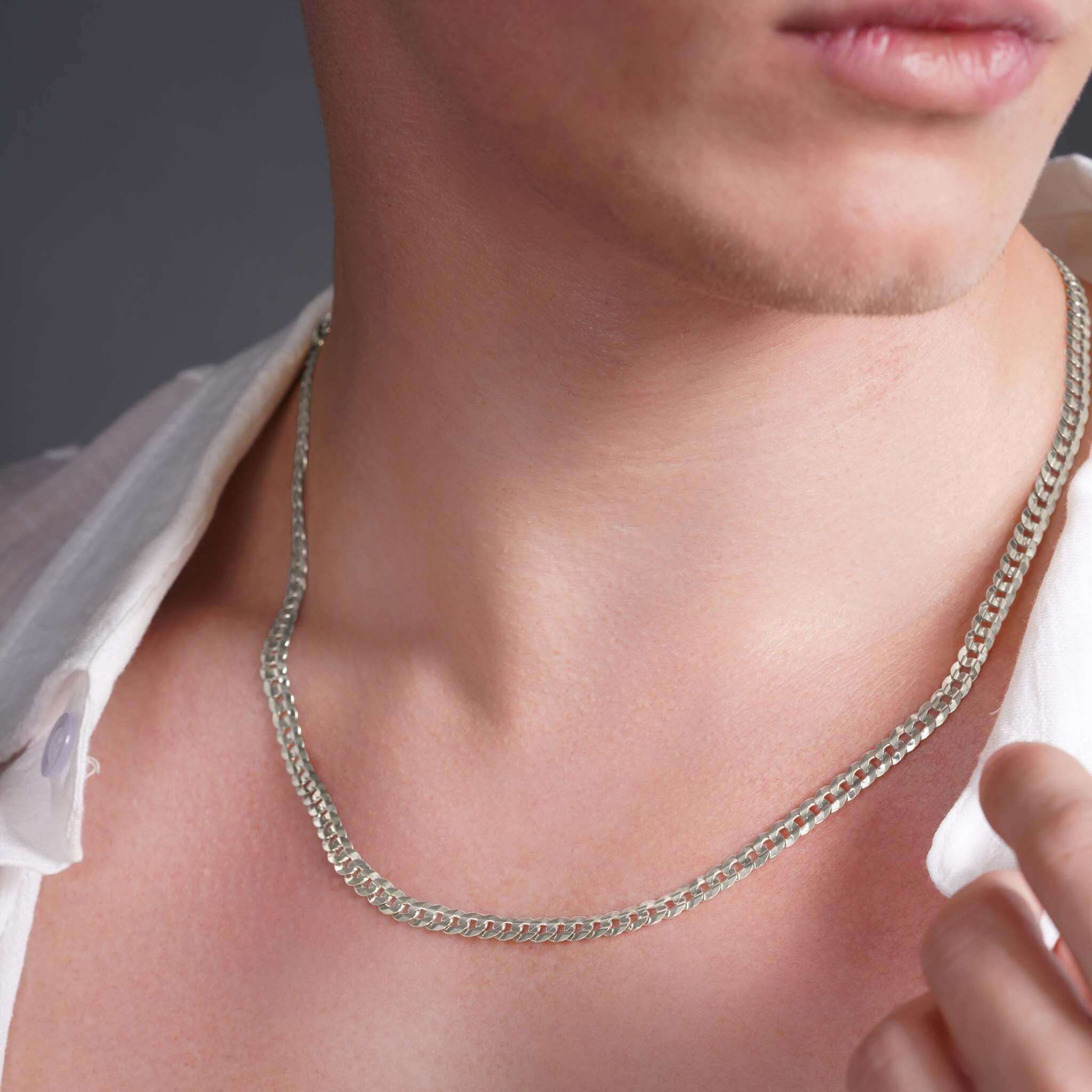 Close-up of a man wearing a men's solid gold curb chain necklace, showcasing its sleek design and shine.